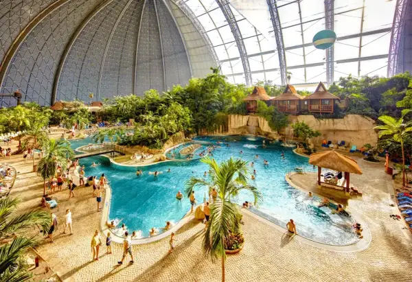 Wielki basen Tropical Island w Berlinie, z palmami, wodospadami i domkami na wodzie.