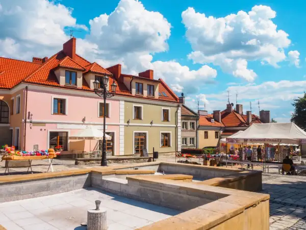 Sandomierz rynek tętni życiem. Kolorowe kamienice, stragany z pamiątkami i błękitne niebo tworzą malowniczy widok.