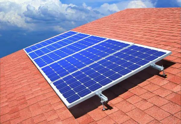 Paneles solares azules sobre un tejado rojo, capturando la energía del sol. ¿Quién inventó las placas solares?