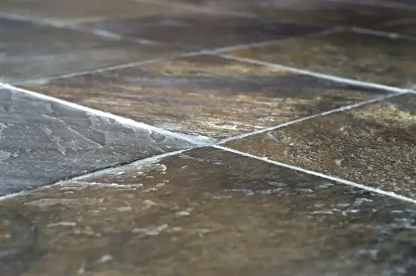 Primo piano di una pavimentazione in pietra di lavagna, con le sue venature naturali e le fughe bianche che creano un motivo geometrico.