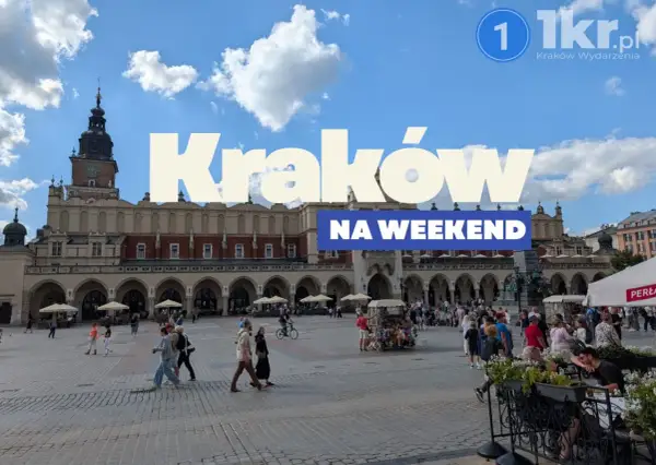 Tłum ludzi spaceruje po Rynku Głównym w Krakowie, ciesząc się piękną pogodą. Widać Sukiennice i wieżę Ratuszową.