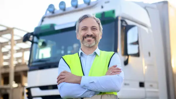 Un chauffeur souriant, en gilet fluo, prêt pour son passage aux mines poids lourds.
