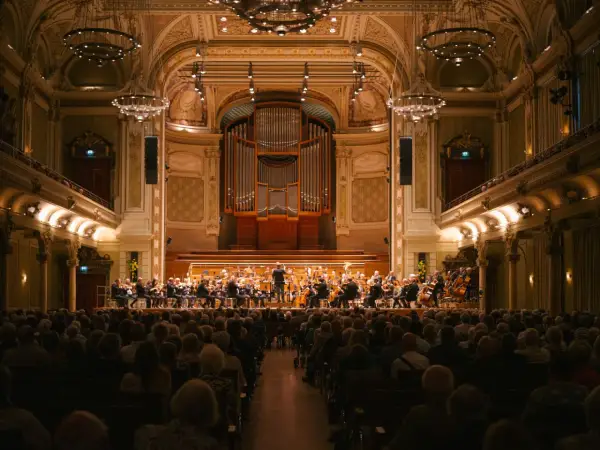Ein Orchester spielt im prunkvollen Saal des Opernhauses Wuppertal vor einem begeisterten Publikum.