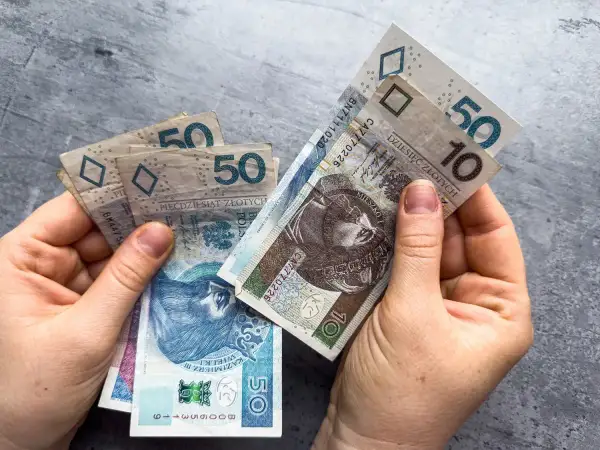 Dłonie trzymają polskie banknoty 10 i 50 zł. Sprawdź, kto może starać się o ponowne przeliczenie emerytury.