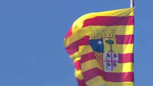 Bandera de San Jorge de Aragón ondeando con orgullo contra el cielo azul.