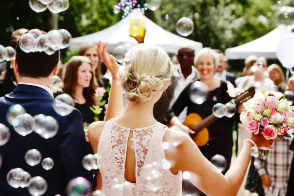 Une marraine, entourée de bulles, tient un bouquet de roses. Une femme joue de la guitare en arrière-plan.