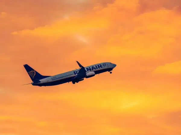 Samolot Ryanair wznosi się na tle pomarańczowego nieba. Idealny na krótkie wycieczki 4 dniowe samolotem.