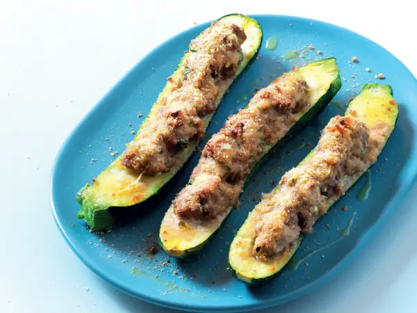 Zucchine tonde ripiene di carne, cotte al forno e servite su un piatto blu.