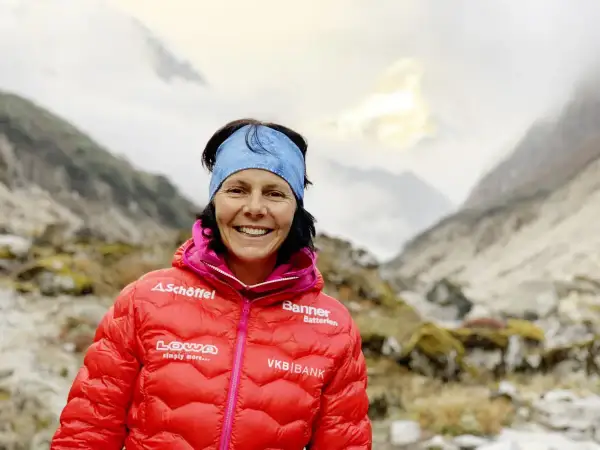 Kristin Harila, bereit für den K2, lächelt in die Kamera, umgeben von majestätischen Bergen.