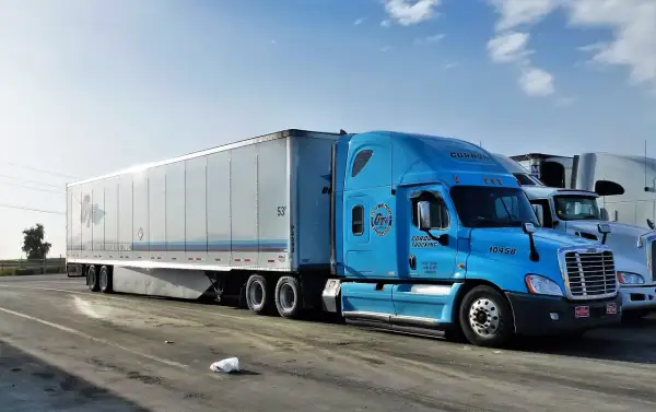 Błękitna ciężarówka Gordon Trucking z naczepą, gotowa do podróży door to door.