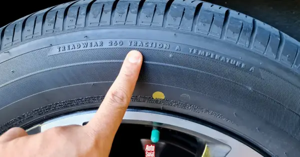 Palec wskazuje żółtą kropkę na oponie, obok napisu "TRACTION A".