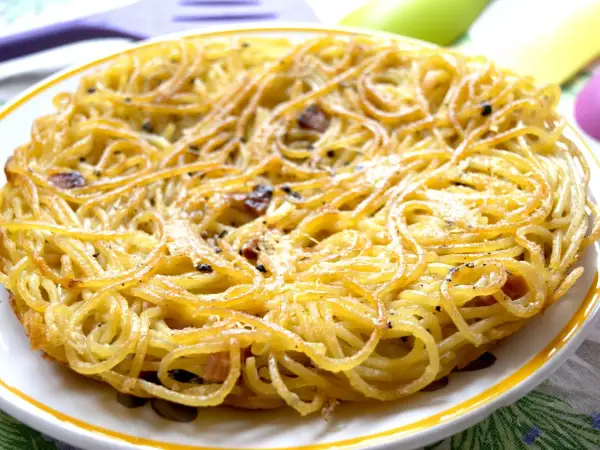 Una dorata frittata di scammaro, con spaghetti croccanti e pezzetti di pancetta, pronta per essere gustata.