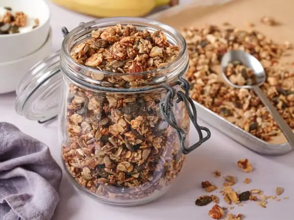 Ein Glas voller knusprigem, selbstgemachtem Granola ohne Zucker, mit Nüssen und Kernen. Perfekt für ein gesundes Frühstück.