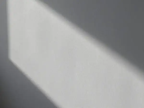Światło podkreśla nierówności na elewacji, tworząc cień o geometrycznym kształcie.