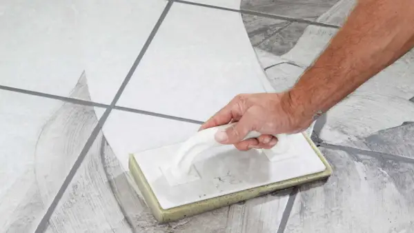Main tenant, quand nettoyer carrelage après joint, utilise une éponge pour enlever l'excès de mortier.