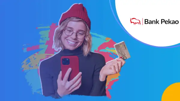 Uśmiechnięta młoda kobieta z telefonem i kartą Banku Pekao. Jej konto przekorzystne zawsze pod ręką!