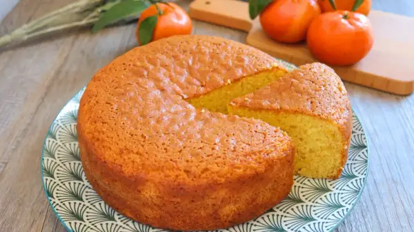 Bizcocho de mandarina esponjoso y dorado, con una porción cortada, listo para disfrutar.