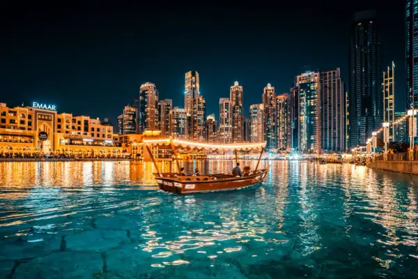 En båt glider fram på vattnet i Dubai i december, med upplysta skyskrapor som bakgrund.
