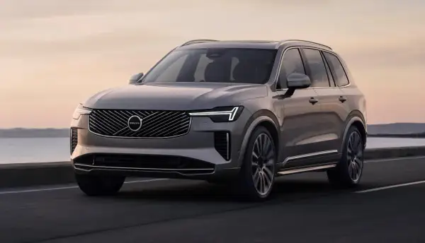 Elegancki, szary Volvo XC90 T8 sunie po drodze przy zachodzie słońca.