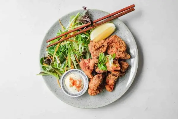 Chrupiący kurczak karaage z sałatką i dipem. Pałeczki czekają, by zacząć ucztę.