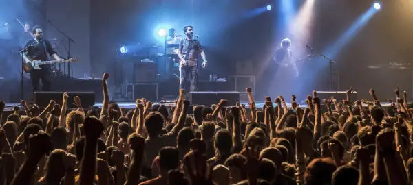 Una banda en vivo toca para una multitud eufórica. Los **fiz horarios** de la música llenan el aire mientras los fans levantan los puños.