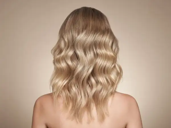Piękne, falowane beżowe blond włosy opadające na ramiona.