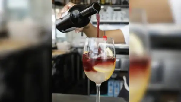Rotwein wird in ein Glas mit Eis, Zitrone und Kirsche gegossen. Perfekt für rotwein im sommer.