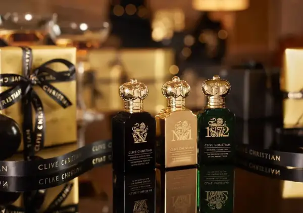 Trzy butelki najdroższych perfum Clive Christian w złotych opakowaniach, ozdobione czarną wstążką z logo marki.