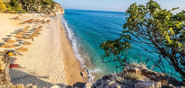 Piękna plaża w Albanii z turkusową wodą i rzędami parasoli. Ceny wakacji w Albanii są przystępne, a widoki zachwycające.