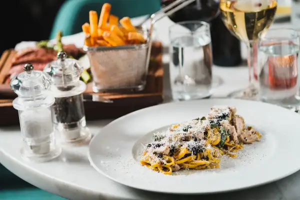 En tallrik med typisk italiensk mat: pasta med kyckling och parmesan, serverad med pommes frites och vin.