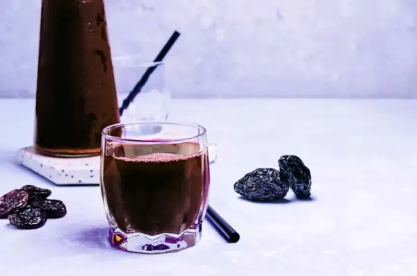 Un verre de jus de pruneau, quelques pruneaux secs et une carafe. Un vrai plaisir pour le temps d'un jus de pruneau.