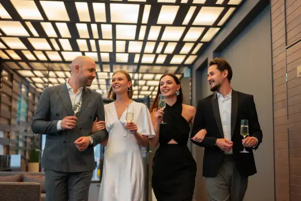 Elegancka para i ich znajomi, świętujący przy szampanie. Wszyscy przestrzegają nienagannego dress code'u na wieczorne wyjście.