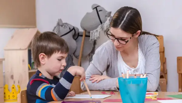 Nauczycielka wspiera chłopca z zespołem Aspergera w rysowaniu. Skupienie na zadaniu, a nie na tym, jak karać dziecko z zespołem Aspergera.