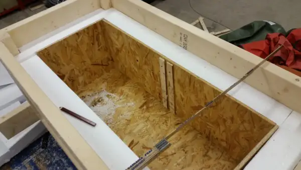Wooden frame with OSB interior, insulated with white foam. A pencil and ruler are visible.