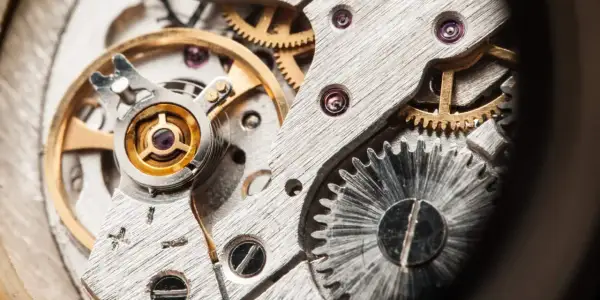 Detalle de un mecanismo de reloj, mostrando engranajes y el volante, que es un oscilador, en su interior.