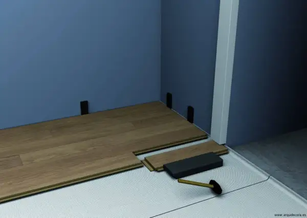 Instalación de suelo laminado con tacos para rodapiés. Se aprecian varios tipos de rodapiés y herramientas para su colocación.