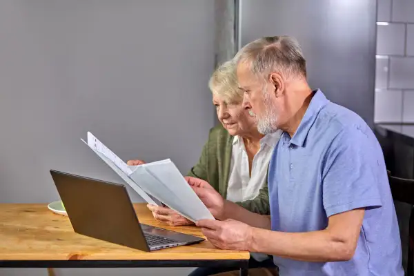 Para seniorów analizuje dokumenty przy laptopie. To przykład ulgi dla seniora w PIT-37.
