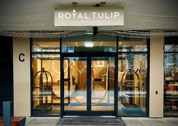 Eleganckie wejście do Royal Tulip Warsaw Apartments z widocznym logo i recepcją.