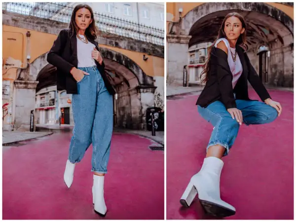 Eleganckie stylizacje z jeansami: kobieta w czarnym blazerze, białej koszulce i luźnych jeansach, uzupełnione białymi botkami na obcasie.