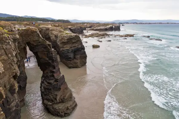 Impresionantes arcos de roca natural en la playa de Ribadeo, con el mar Cantábrico rompiendo suavemente en la arena.