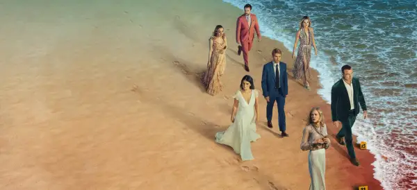En grupp människor i eleganta kläder går längs en strand. Kanske är de det perfekta paret, eller så döljer de mörka hemligheter.