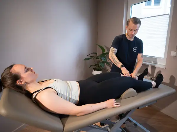Mann führt Lymphdrainage Massage am Bein einer liegenden Frau durch.