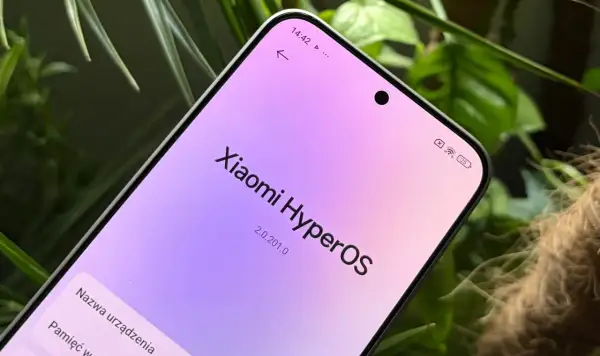 Ekran telefonu z napisem "Xiaomi HyperOS" w pastelowych barwach, otoczony zielenią roślin.