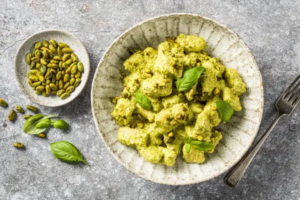 Gnocchis crémeux enrobés d'une sauce pesto onctueuse, parsemés de pistaches concassées et décorés de feuilles de basilic frais. Un délice !