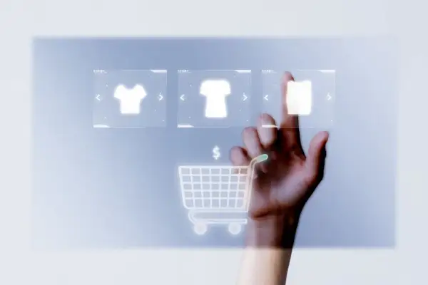 Mano tocando pantalla virtual con iconos de camisetas y carrito de compra. Guía para saber como abrir una tienda online en España.
