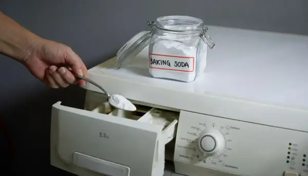 Mano aggiunge bicarbonato di sodio, un ingrediente naturale per la soda per lavatrice, nel cassetto del detersivo.