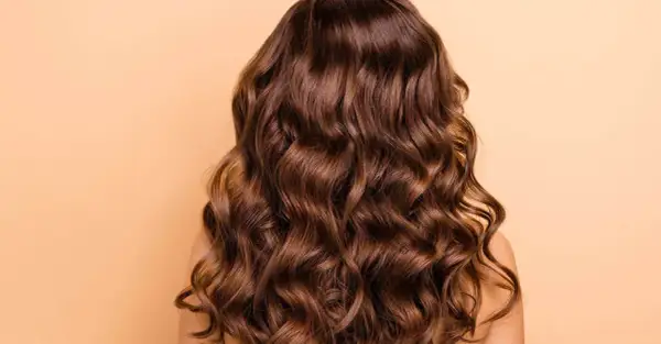 Cabello castaño largo y ondulado, con ondas definidas. Descubre cómo peinar pelo ondulado para lograr este look.