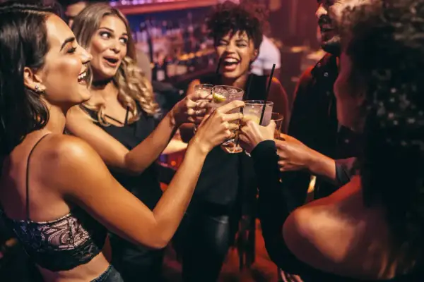 Glada vänner skålar i drinkar, en riktig Zakynthos fest-stämning på en livlig bar.