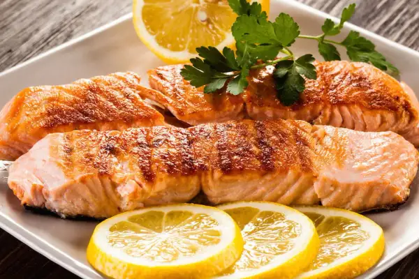 Filetti di salmone succulenti, cotti alla perfezione, con fette di limone e prezzemolo. Un piatto che fa pensare al salmone in gravidanza, ricco di omega-3.