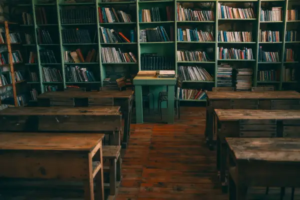 Stare ławki i regały pełne książek tworzą nostalgiczny motyw starej biblioteki lub klasy.